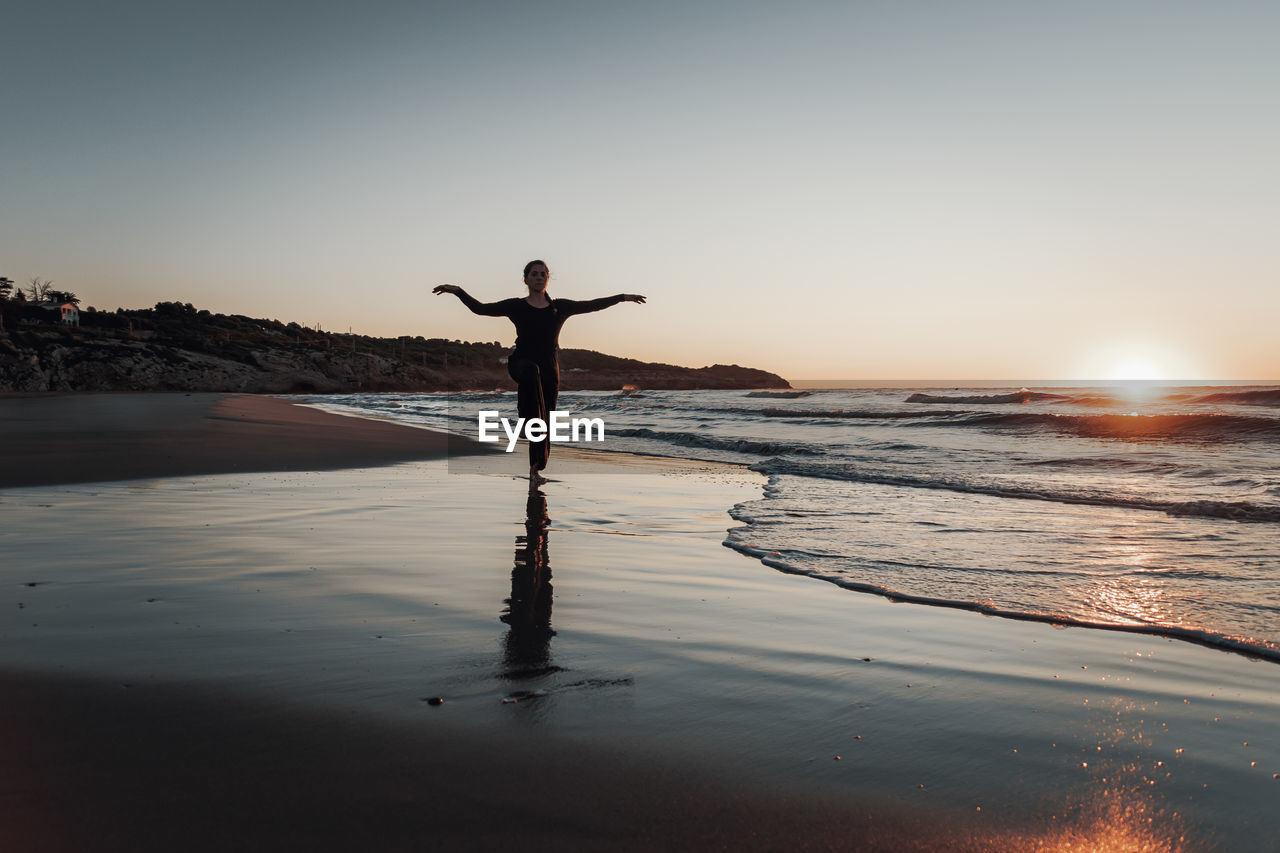 Woman standing on beach during sunrise