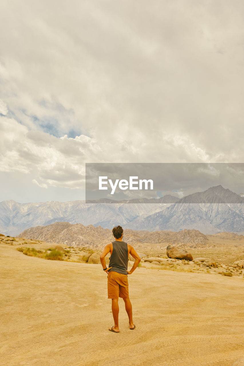 Young man in the california desert looking mountains of alabama hills.