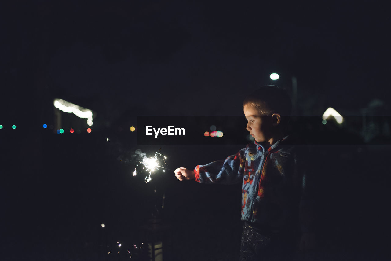 Boy holding sparkler at night