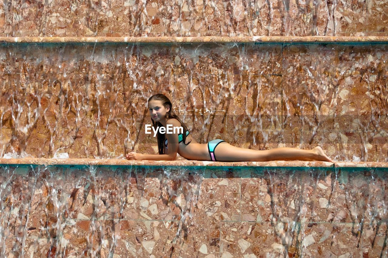 Portrait of seductive woman wearing bikini relaxing on patterned wall