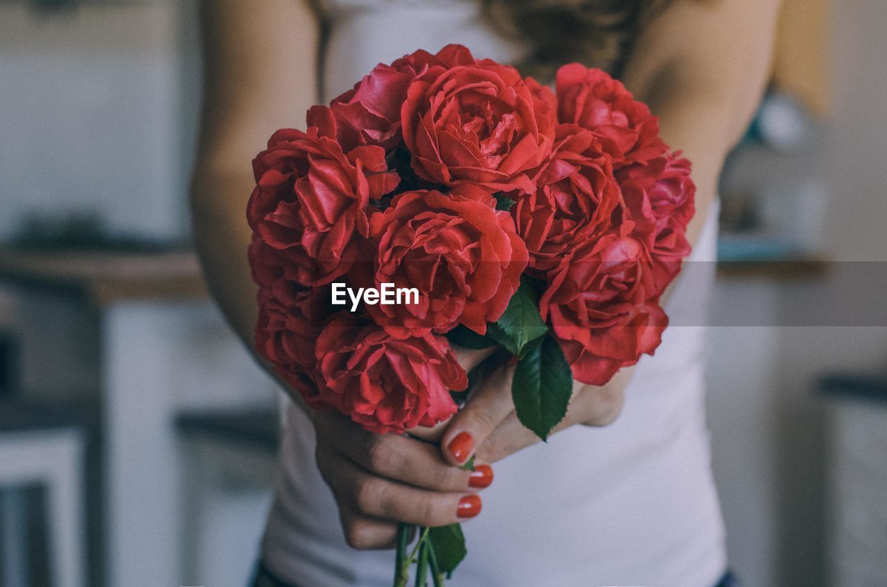 Midsection of woman holding red rose bouquet