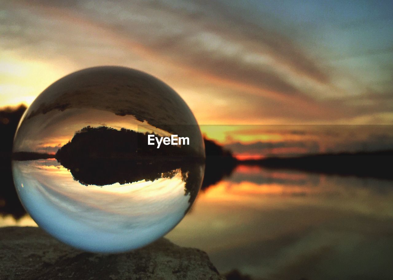 CLOSE-UP OF CRYSTAL BALL ON SEA AGAINST SKY