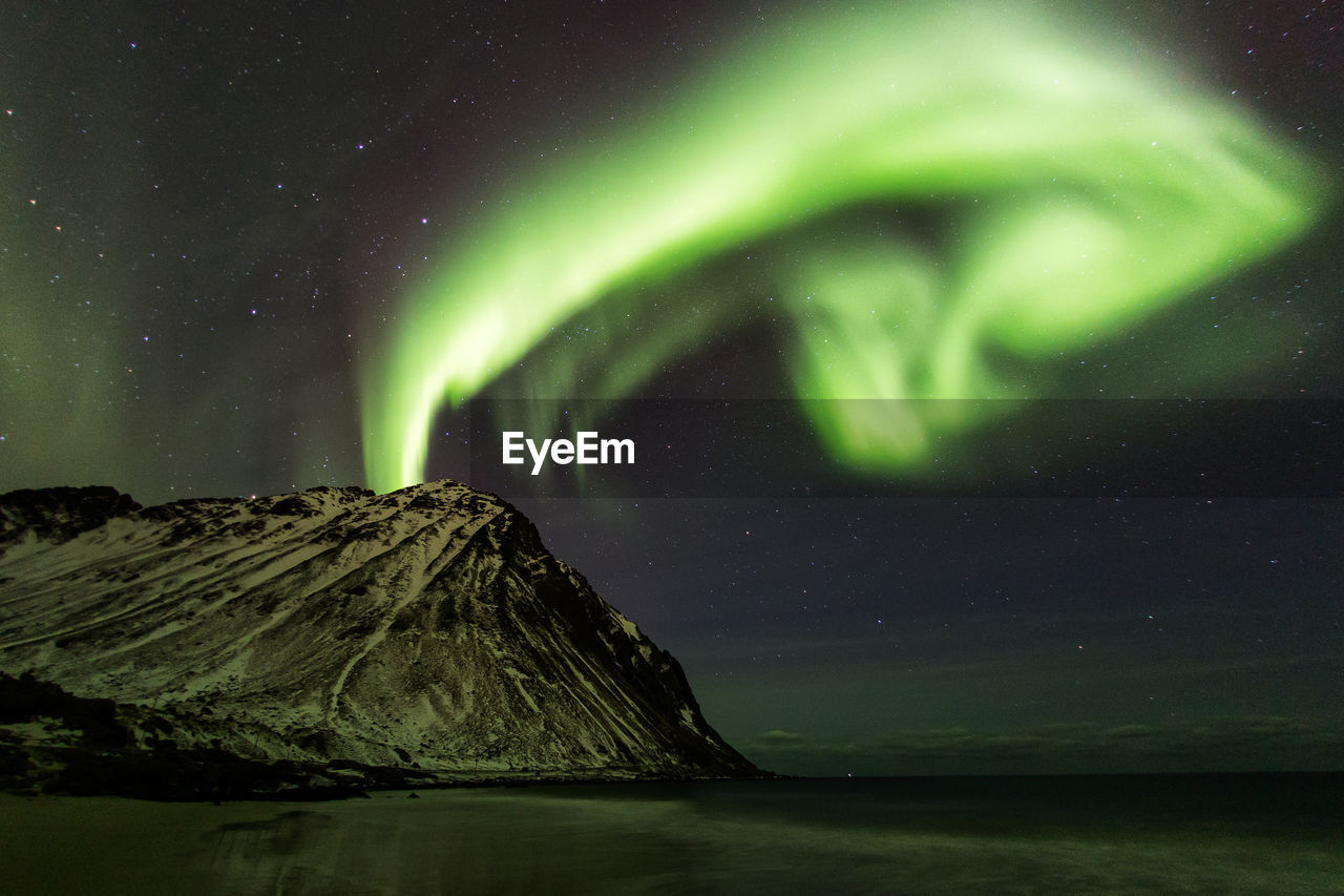 Scenic view of beach against aurora borealis at night