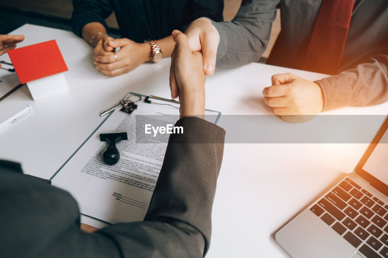 Business colleagues shaking hands at desk in office