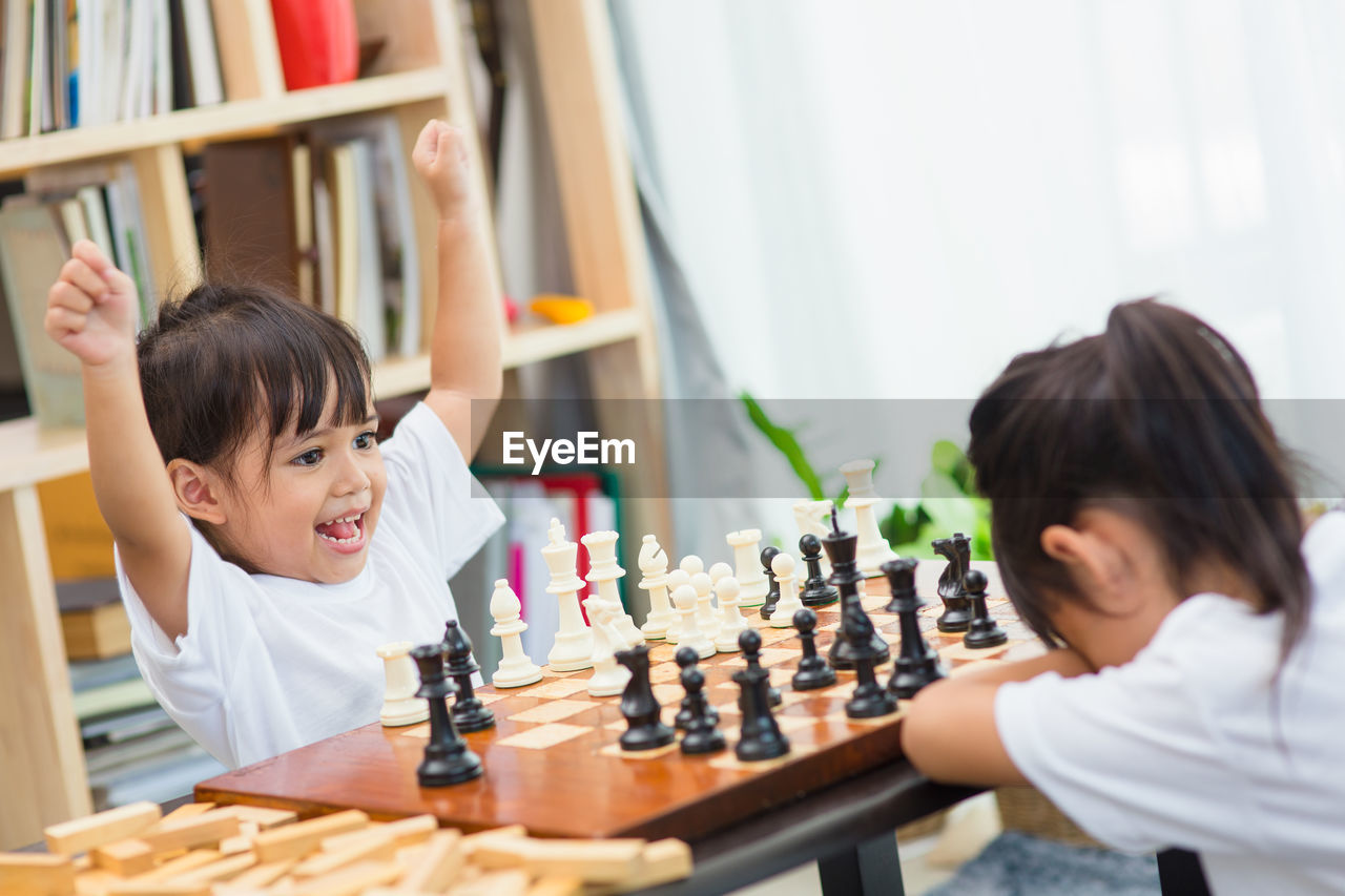 Cute sisters playing chess at home