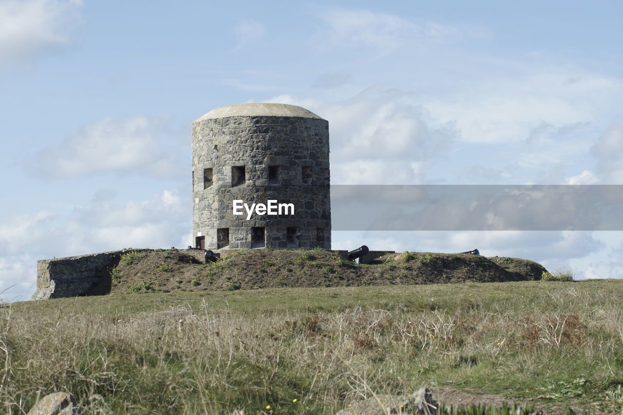 Old ruin building in field against cloudy sky