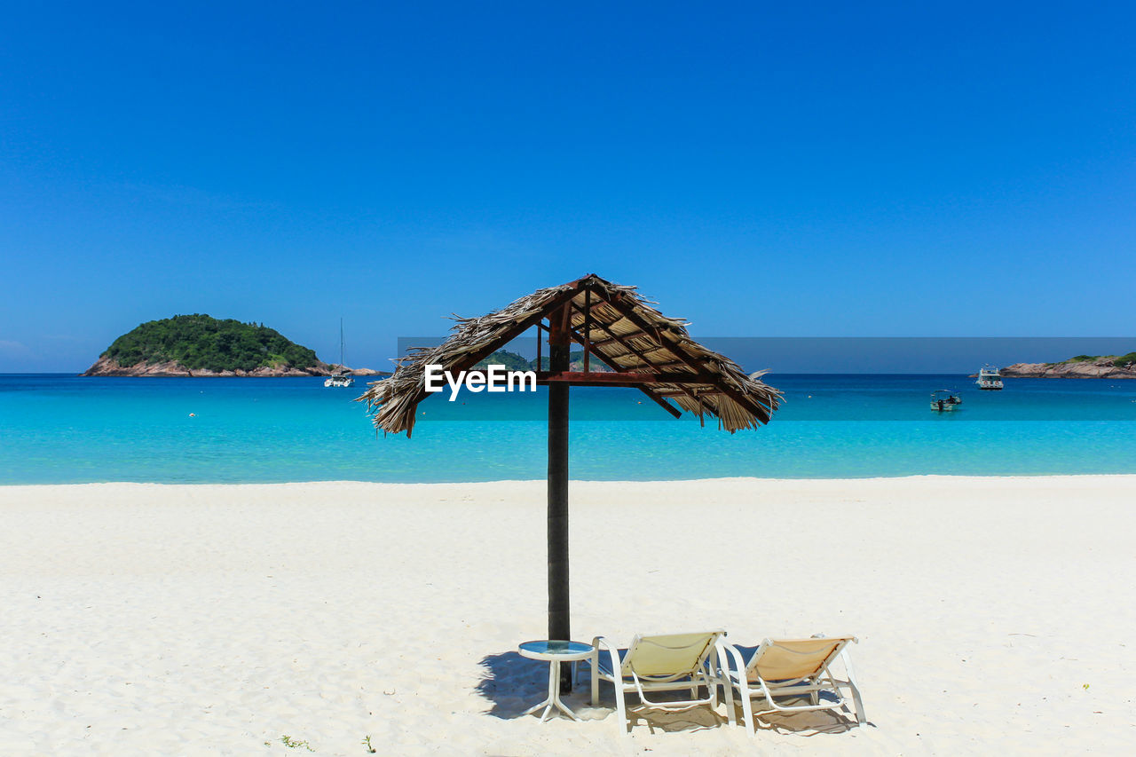 DECK CHAIRS ON BEACH AGAINST CLEAR BLUE SKY