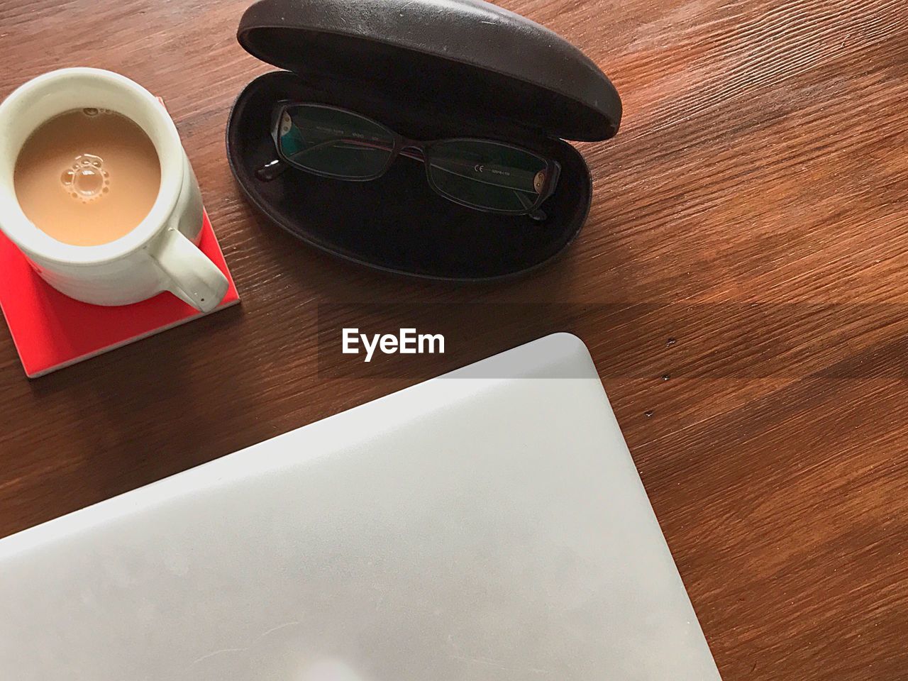 High angle view of coffee, glasses case and laptop on table