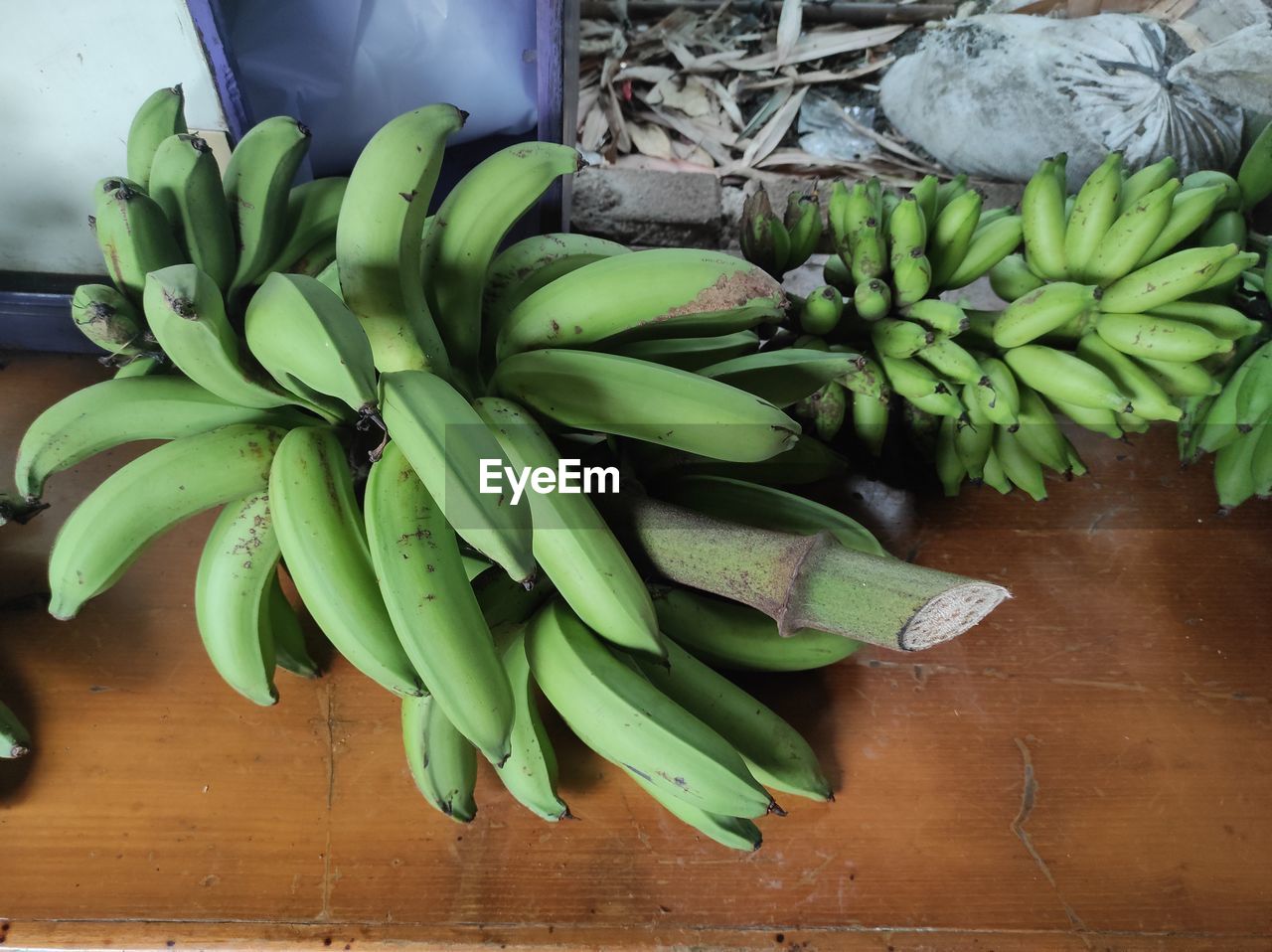 banana, food and drink, food, healthy eating, green, cooking plantain, wellbeing, freshness, flower, produce, bunch, plant, fruit, no people, vegetable, indoors, leaf, plant part, high angle view, raw food, still life, wood, retail, nature, large group of objects, table, organic