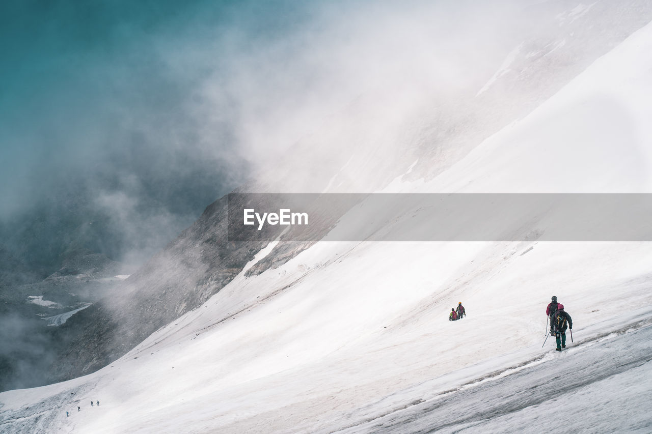 PEOPLE SKIING ON SNOWCAPPED MOUNTAINS