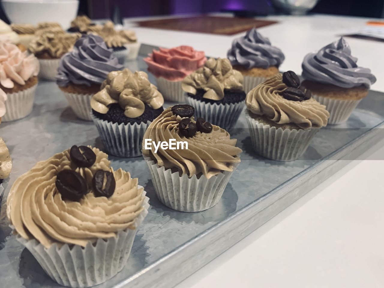 CLOSE-UP OF CUPCAKES ON TABLE AGAINST WALL