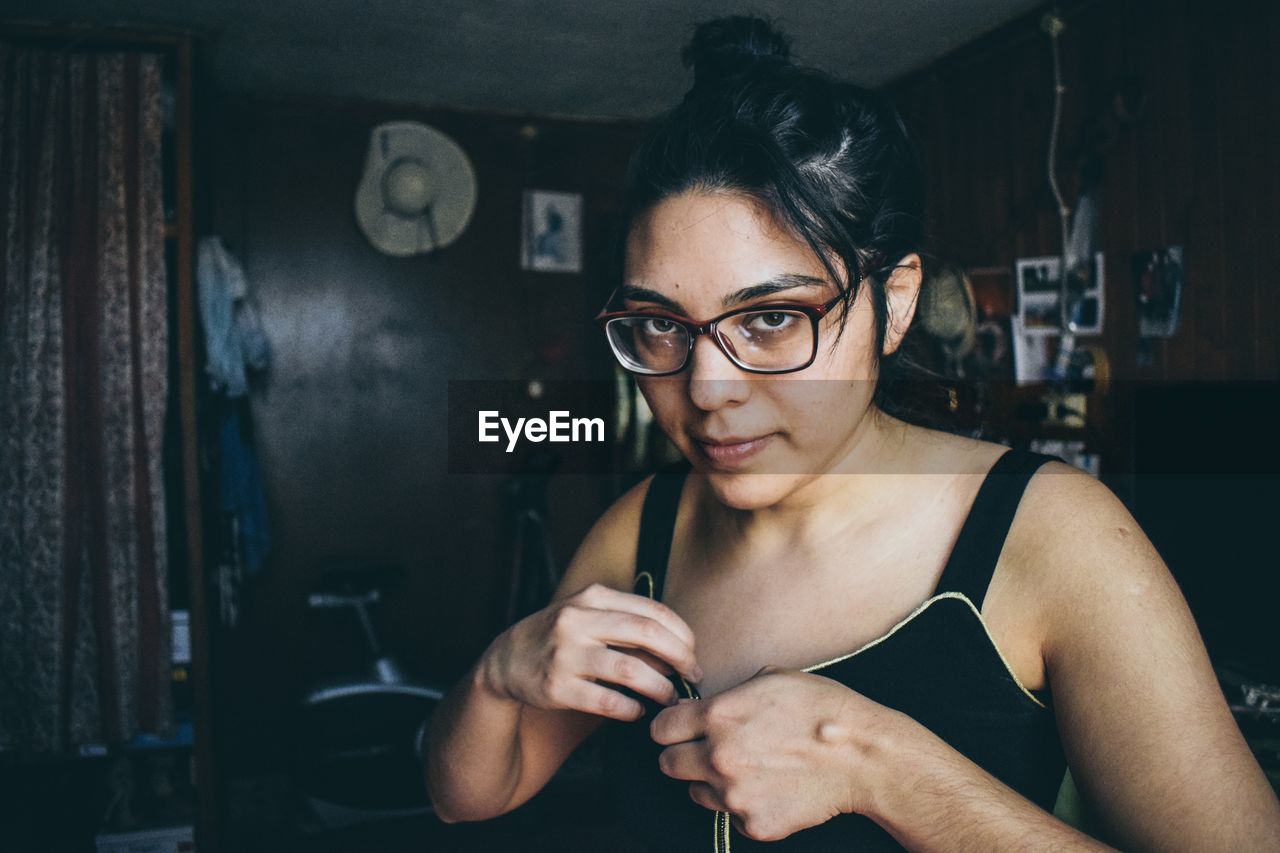 Portrait of young woman wearing eyeglasses at home