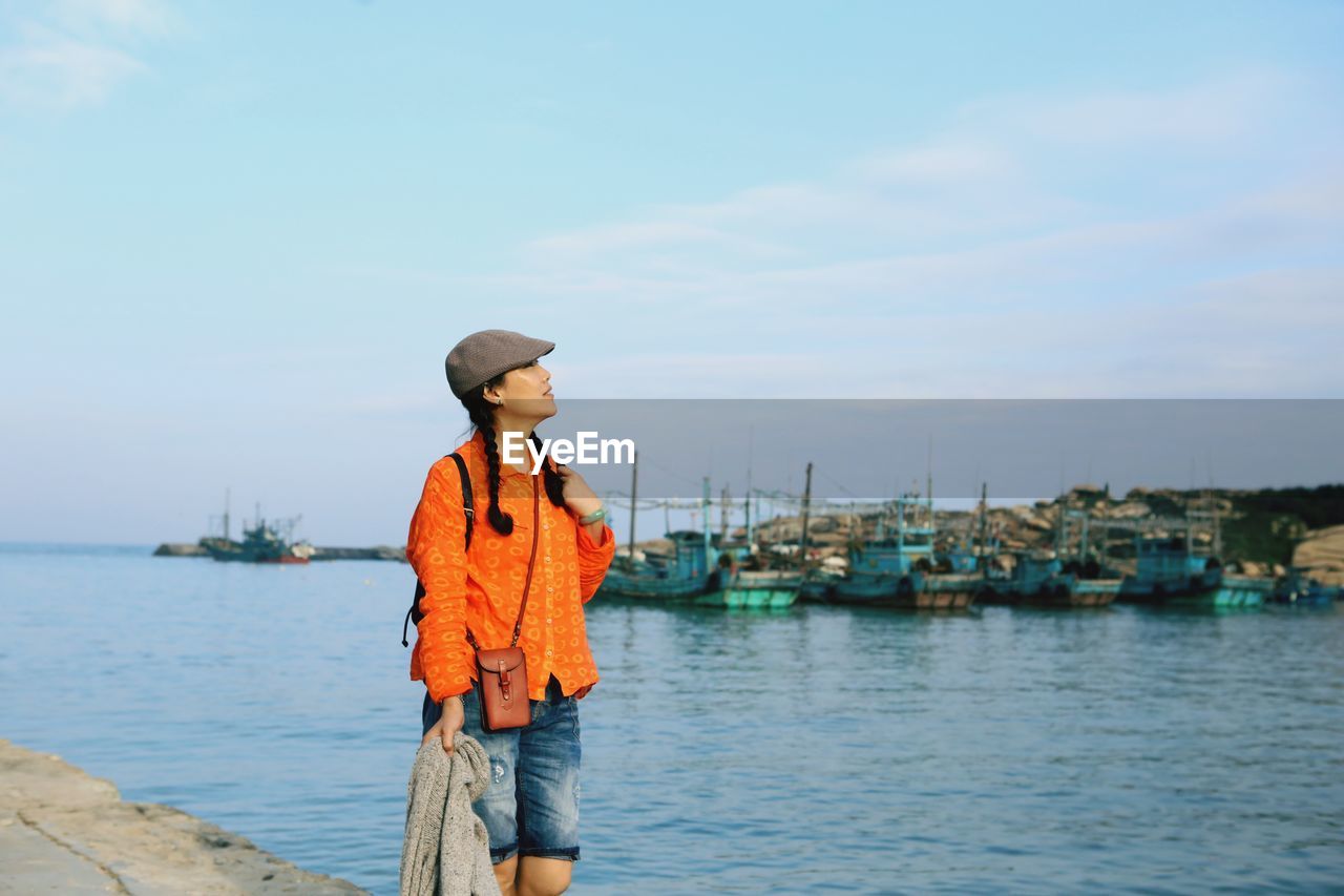 Woman standing at harbor against sky