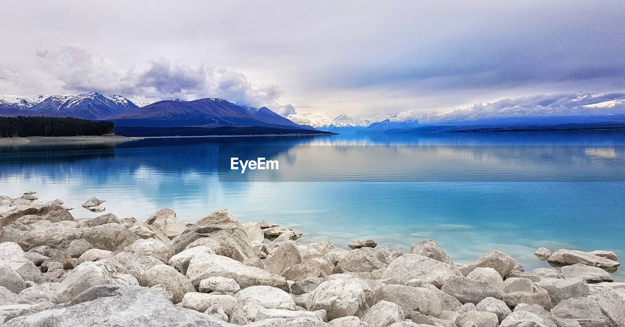 Scenic view of lake by mountains against sky