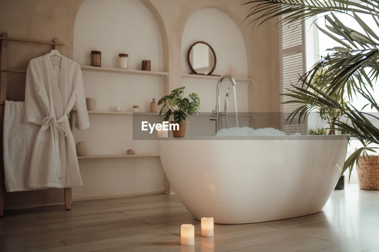 bathtub, indoors, interior design, room, home, domestic room, home interior, luxury, no people, flowerpot, bathroom, domestic bathroom, plant, nature, wealth, flooring, floor, household equipment, lifestyles, potted plant, architecture, window, candle, domestic life, plumbing fixture