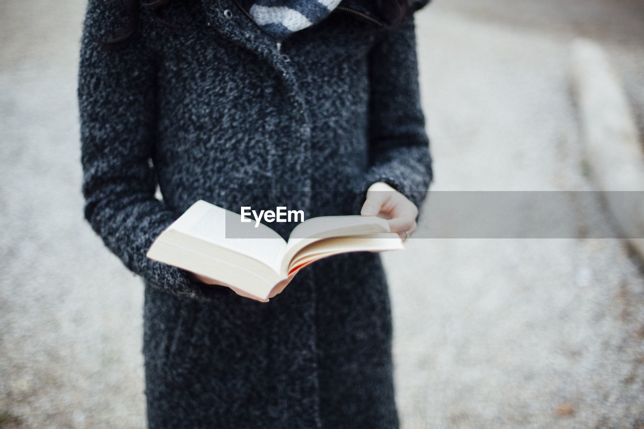 Midsection of woman holding book on field