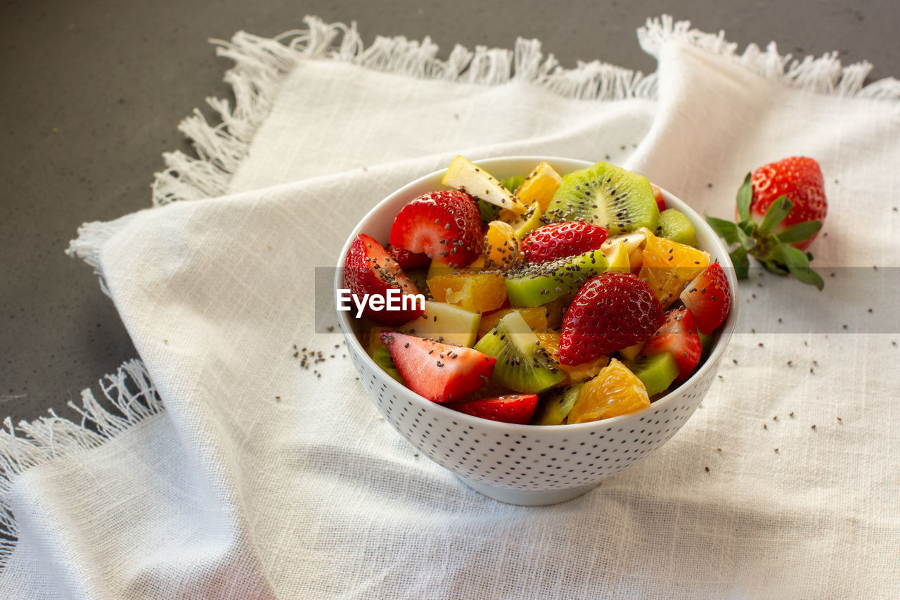 Bowl of healthy fresh fruit salad on white background. top view