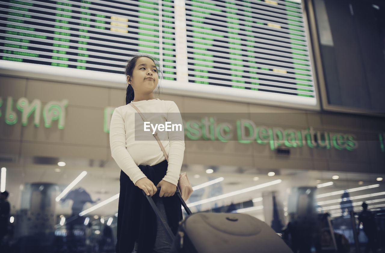 Low angle view of girl looking away while standing at airport
