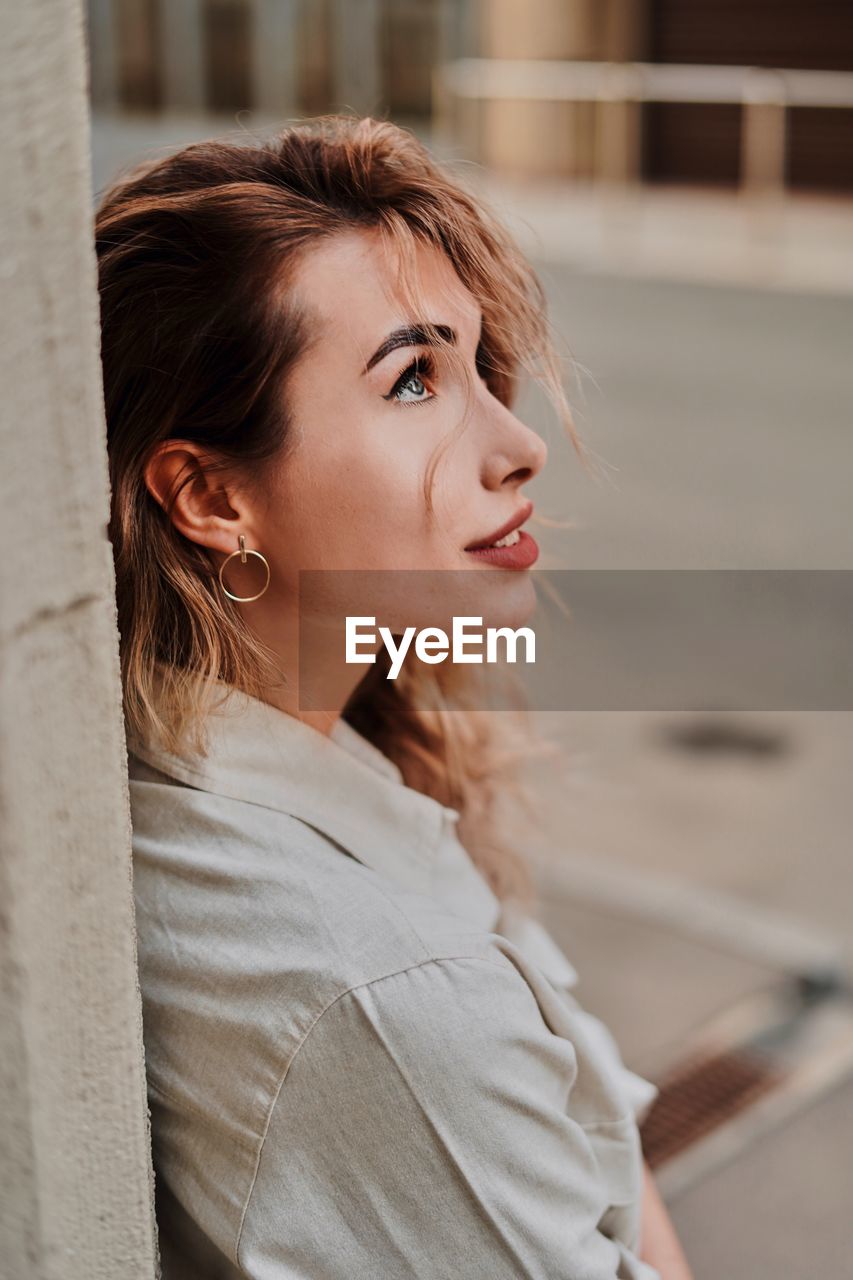 Woman looking away while standing in city