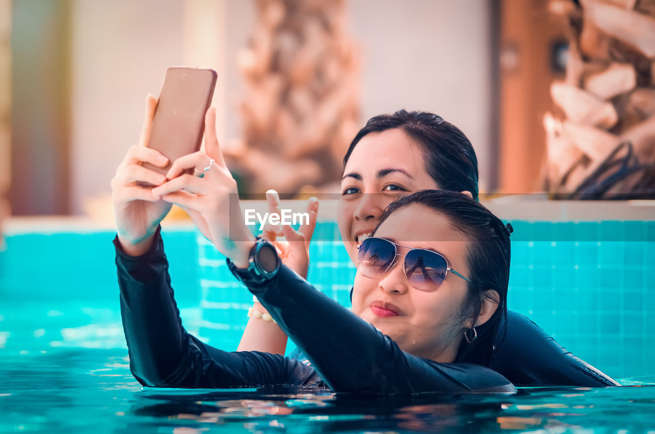 Smiling women taking in swimming pool