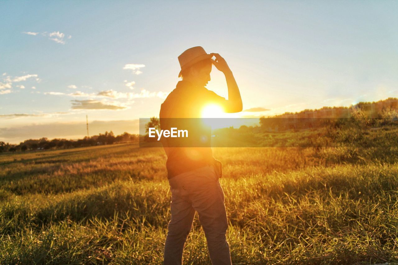 Man standing on field against sky during sunset