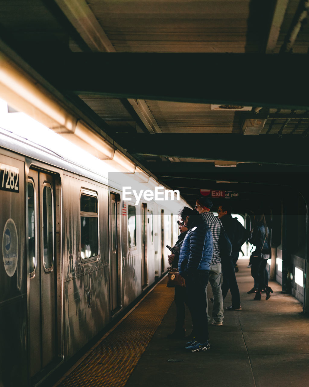 Side view of passengers standing by metro train at subway station