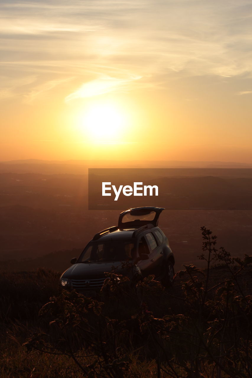 Car on landscape against sunset sky