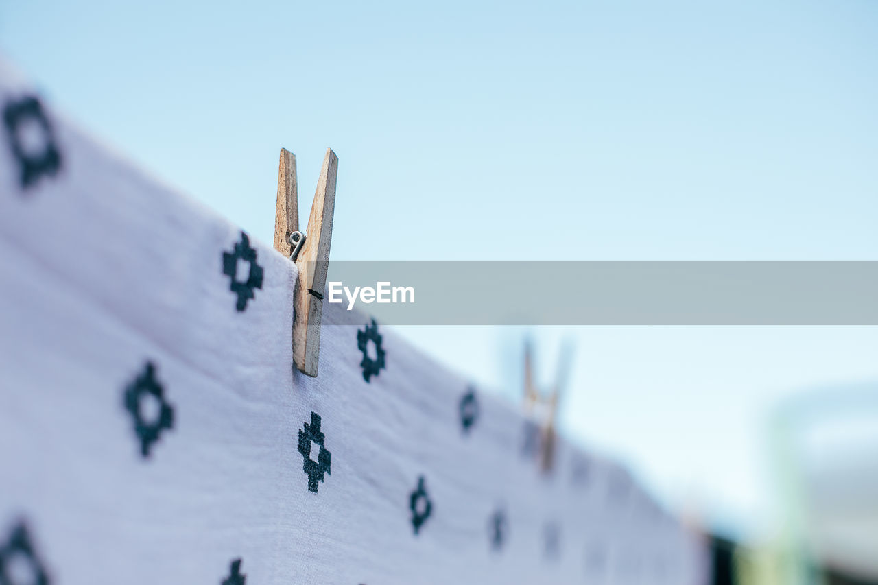 LOW ANGLE VIEW OF CLOTHESPINS AGAINST CLEAR SKY