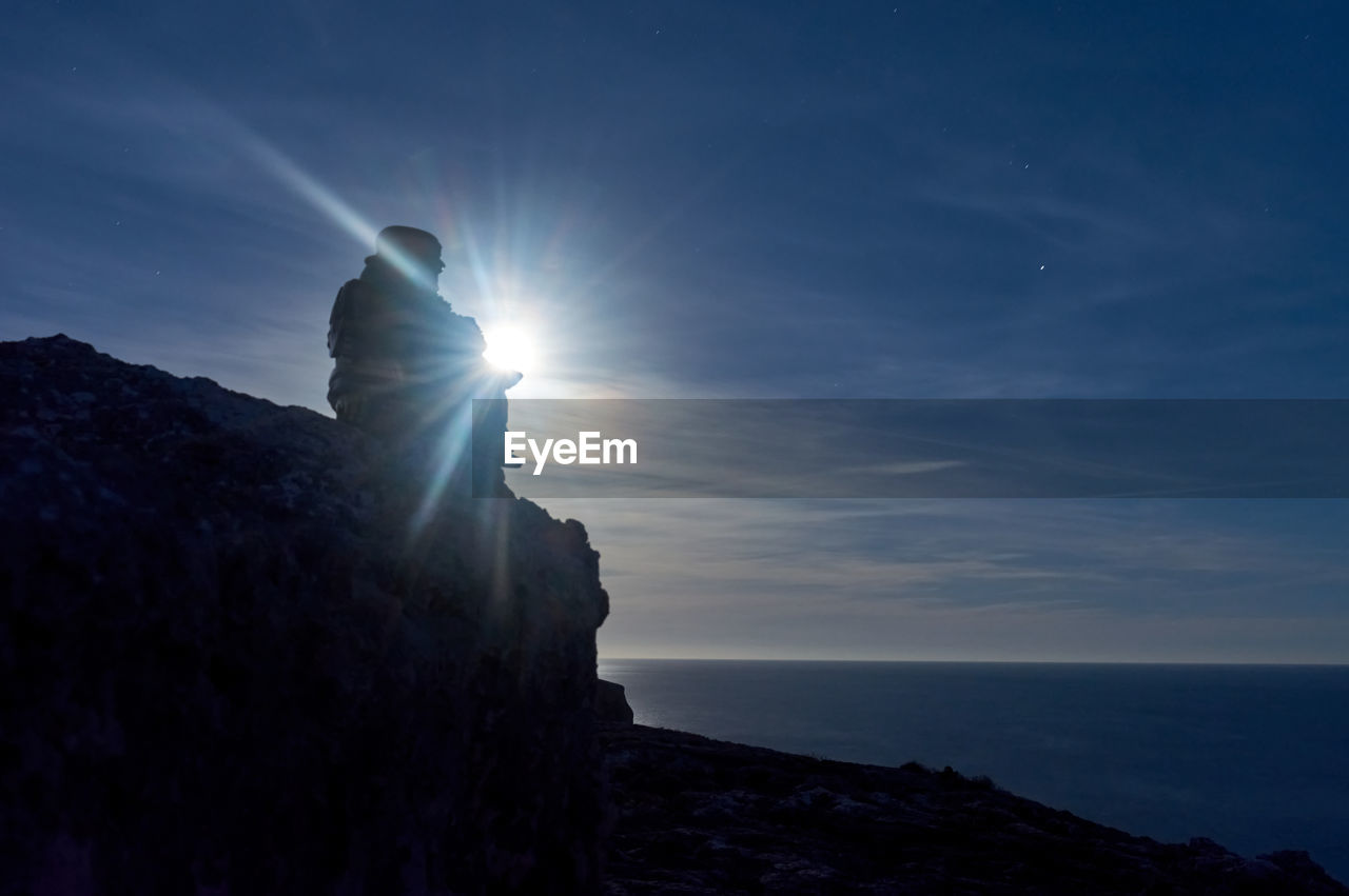 SILHOUETTE ROCKS BY SEA AGAINST SKY