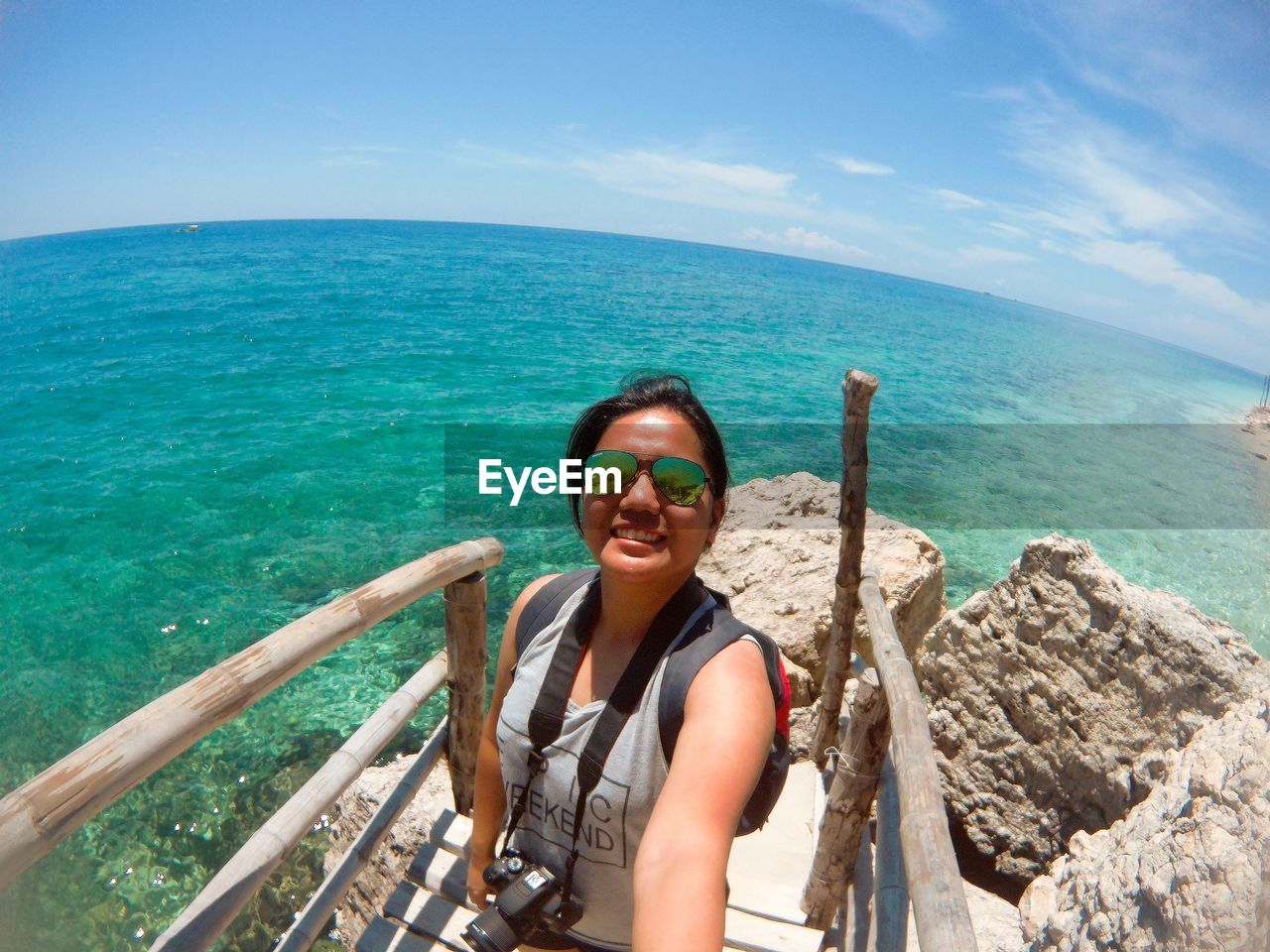 Portrait of young woman standing by sea against sky