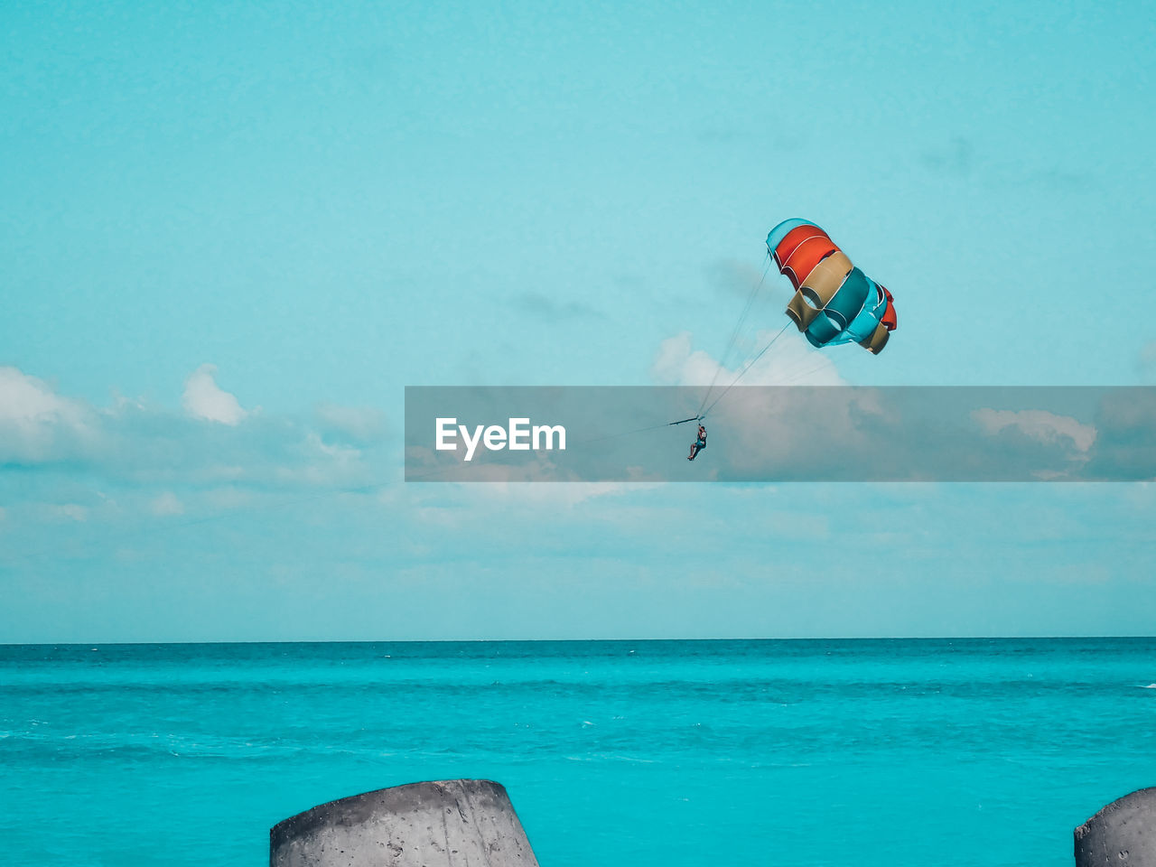 Low angle view of person paragliding over sea against sky