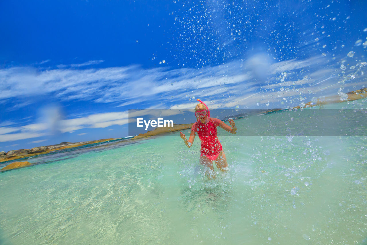 Young woman splashing water in sea