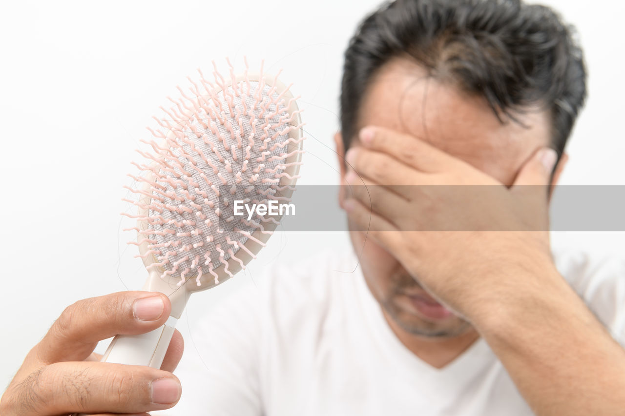 Middle-aged man shows comb brush with loss hair and stressed about his hair loss problems