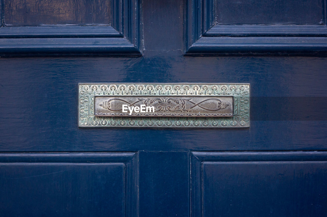 An ornate antique letterbox in a blue wooden front door in london 