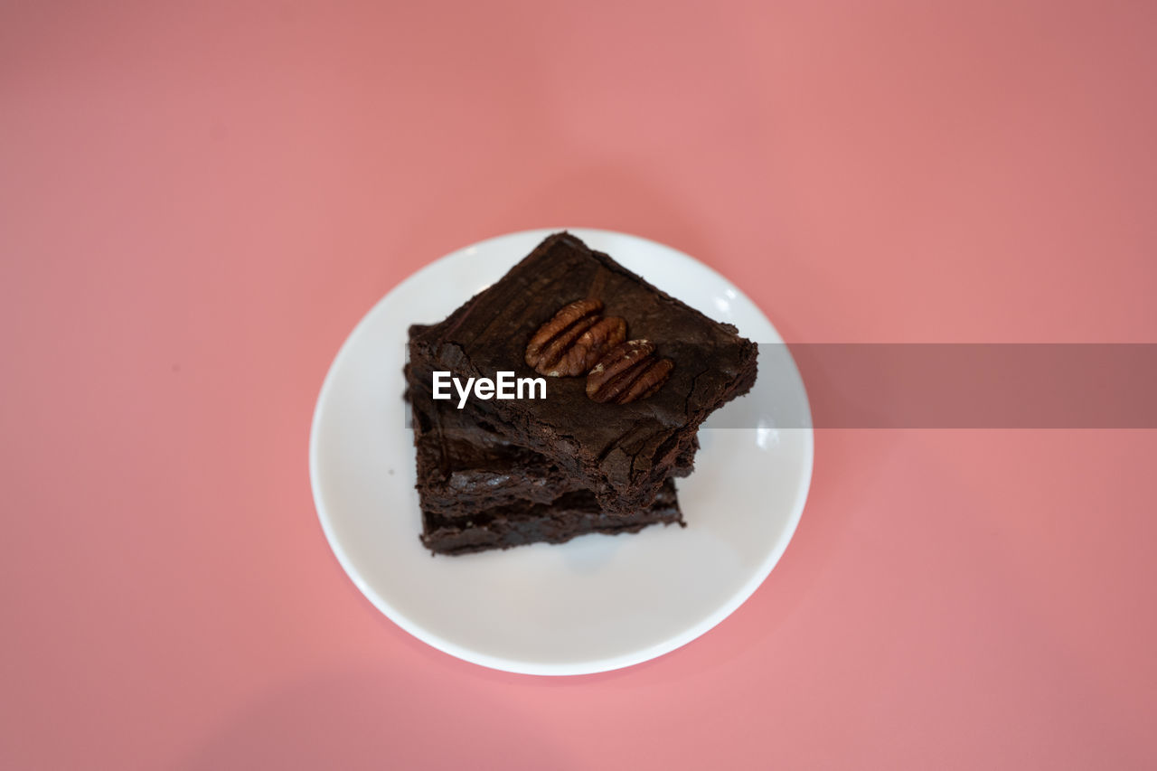 CLOSE-UP OF CAKE SERVED ON PLATE AGAINST RED BACKGROUND