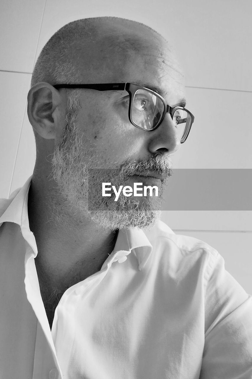 eyeglasses, adult, glasses, white, one person, black and white, headshot, portrait, men, monochrome, vision care, indoors, monochrome photography, facial hair, eyewear, black, mature adult, beard, looking, looking away, human head, person, contemplation, human face, close-up, moustache, lifestyles, side view, profile view
