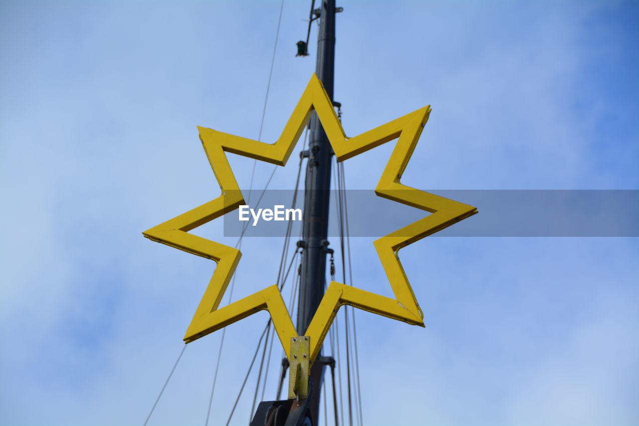 Low angle view of star shape on mast against sky