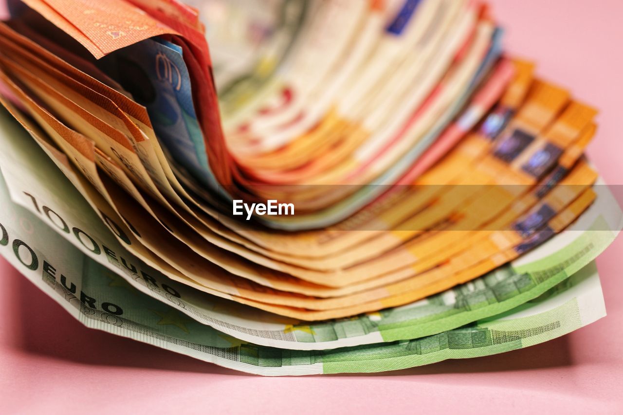 Close-up of paper currency over pink background