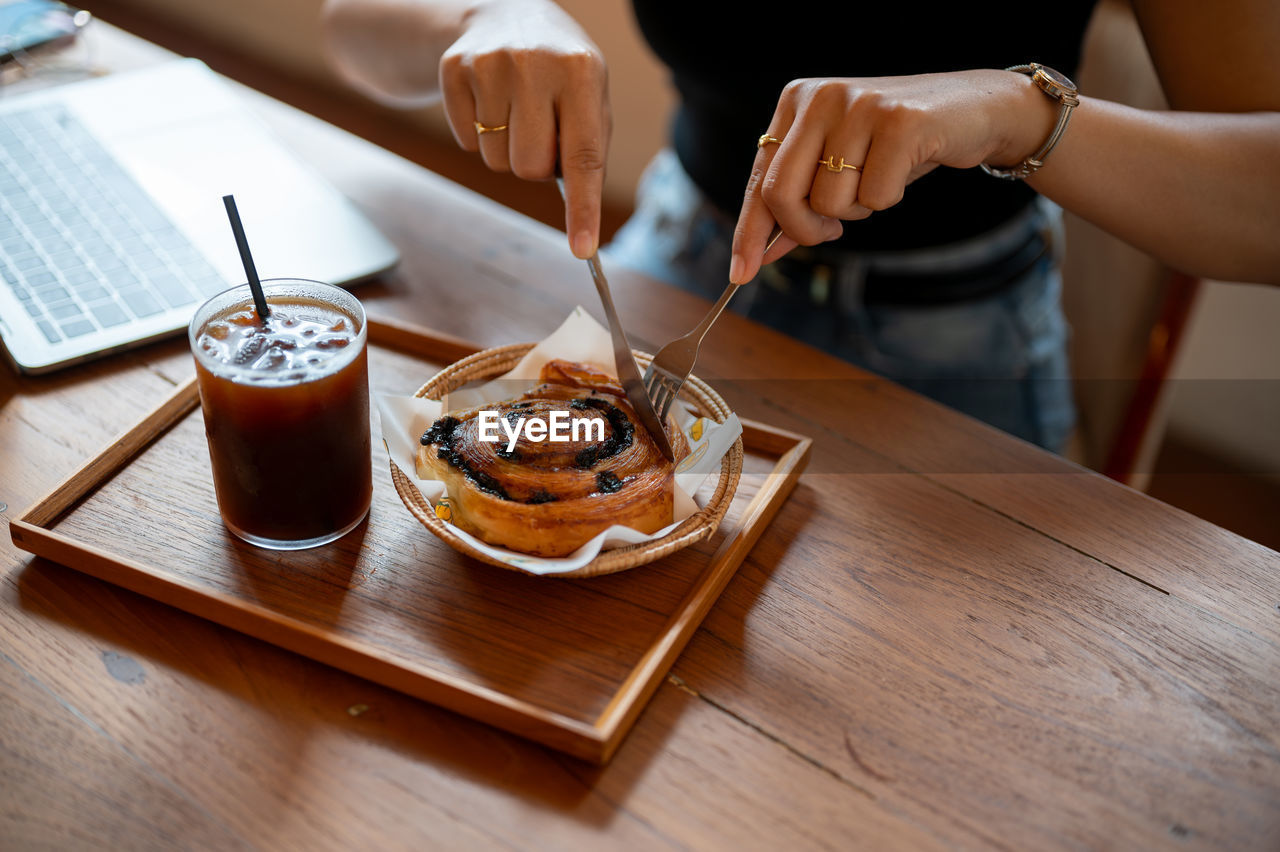 cropped hand of woman having breakfast at table