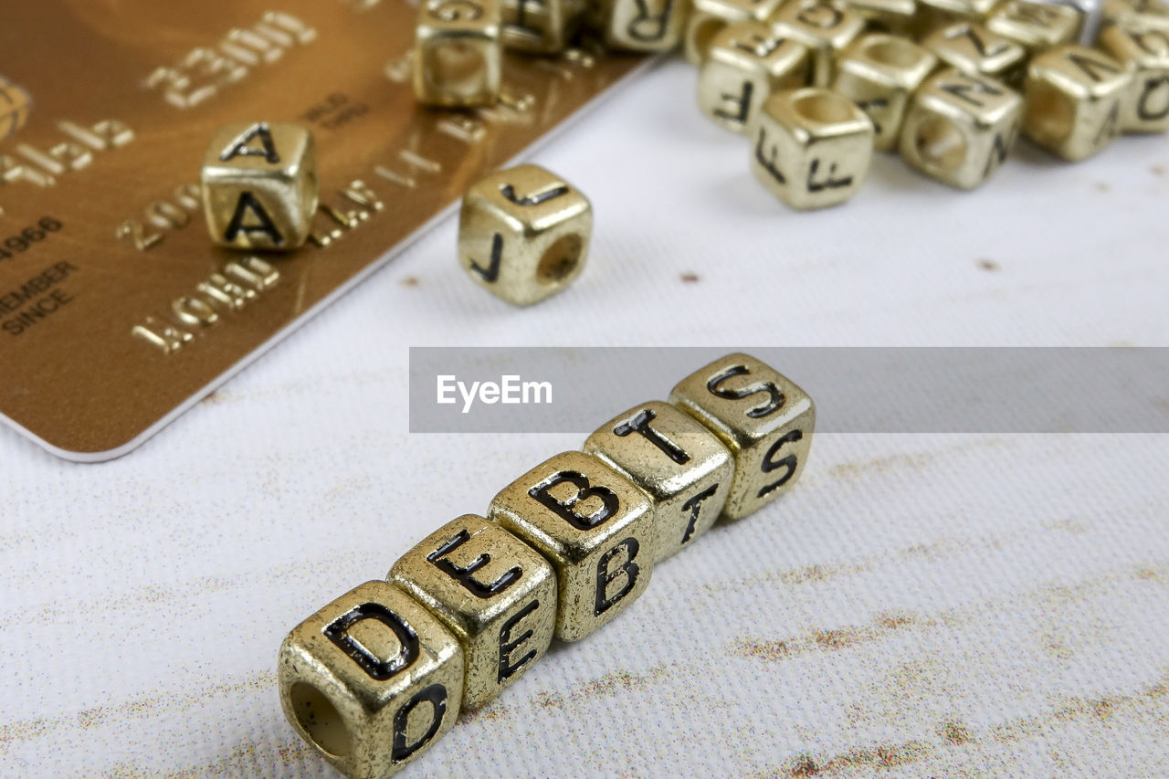 Close-up of debt text made with golden toy blocks on table