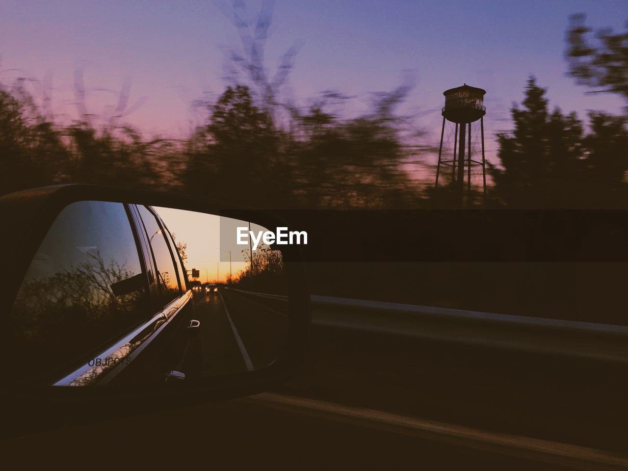 Reflection of car on side-view mirror at sunset