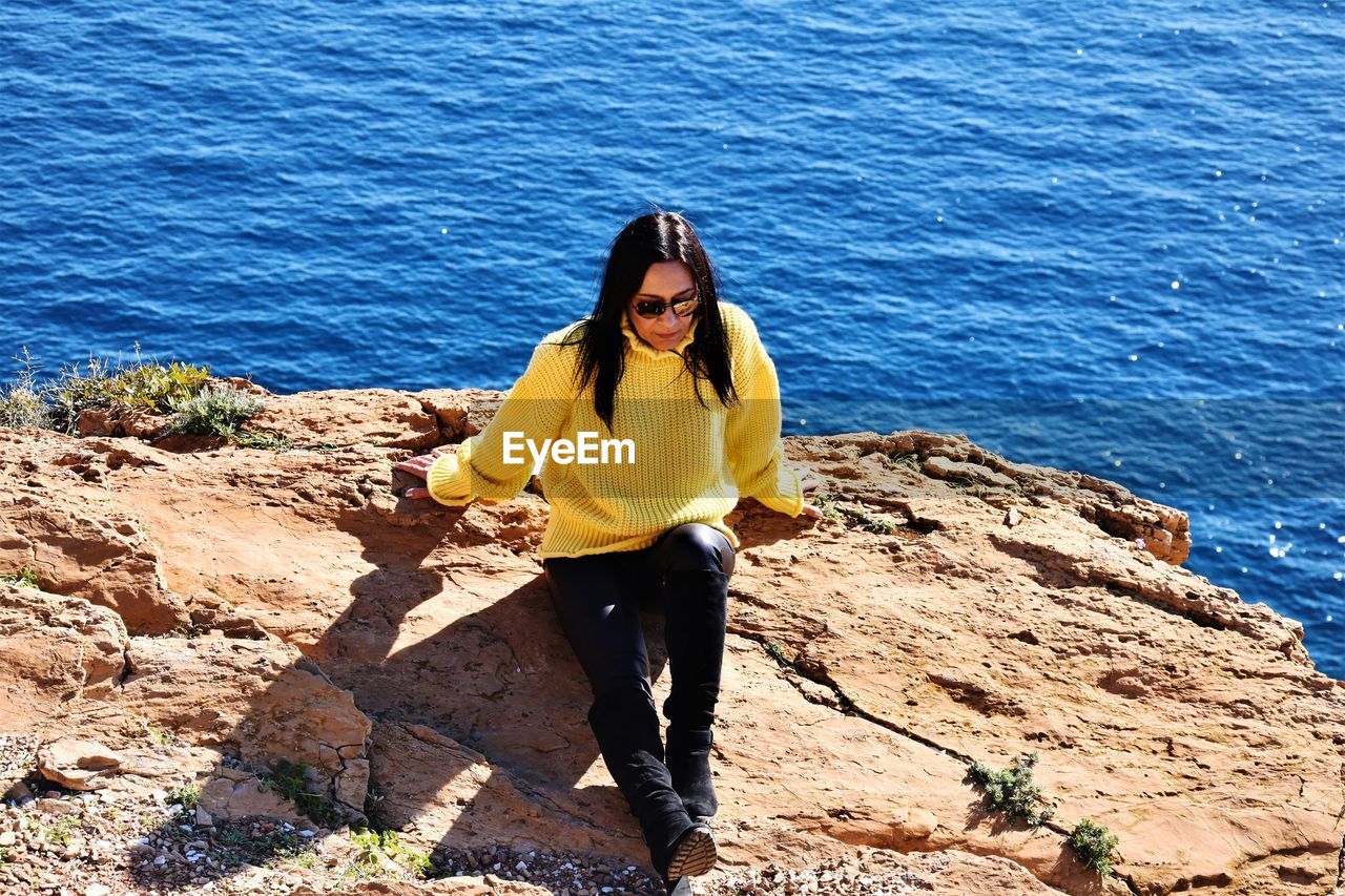 Full length of young woman standing on rock