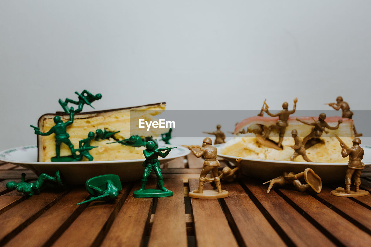 Army of toy soldiers fighting on pieces of cake - close up food on table white background