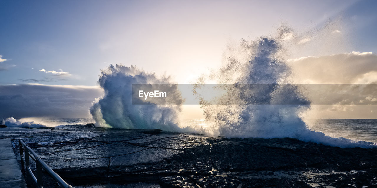 Waves splashing on sea against sky