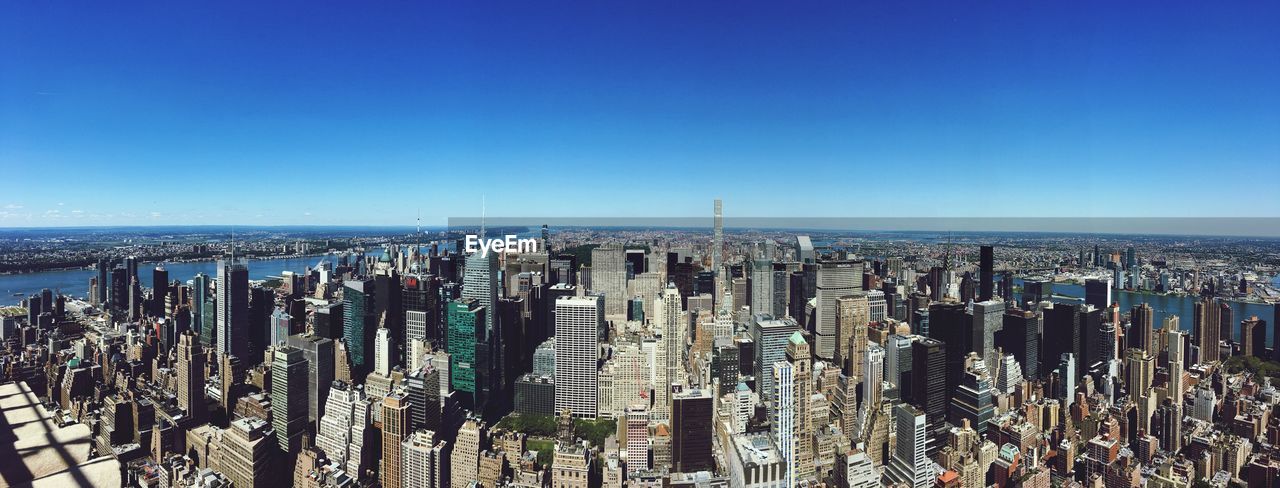 Panoramic view of city against clear blue sky