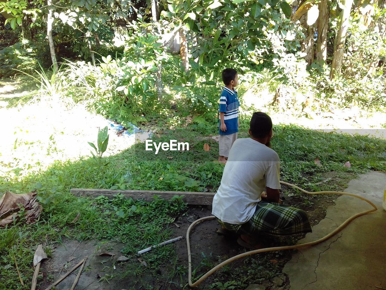 REAR VIEW OF FATHER AND SON BY TREES