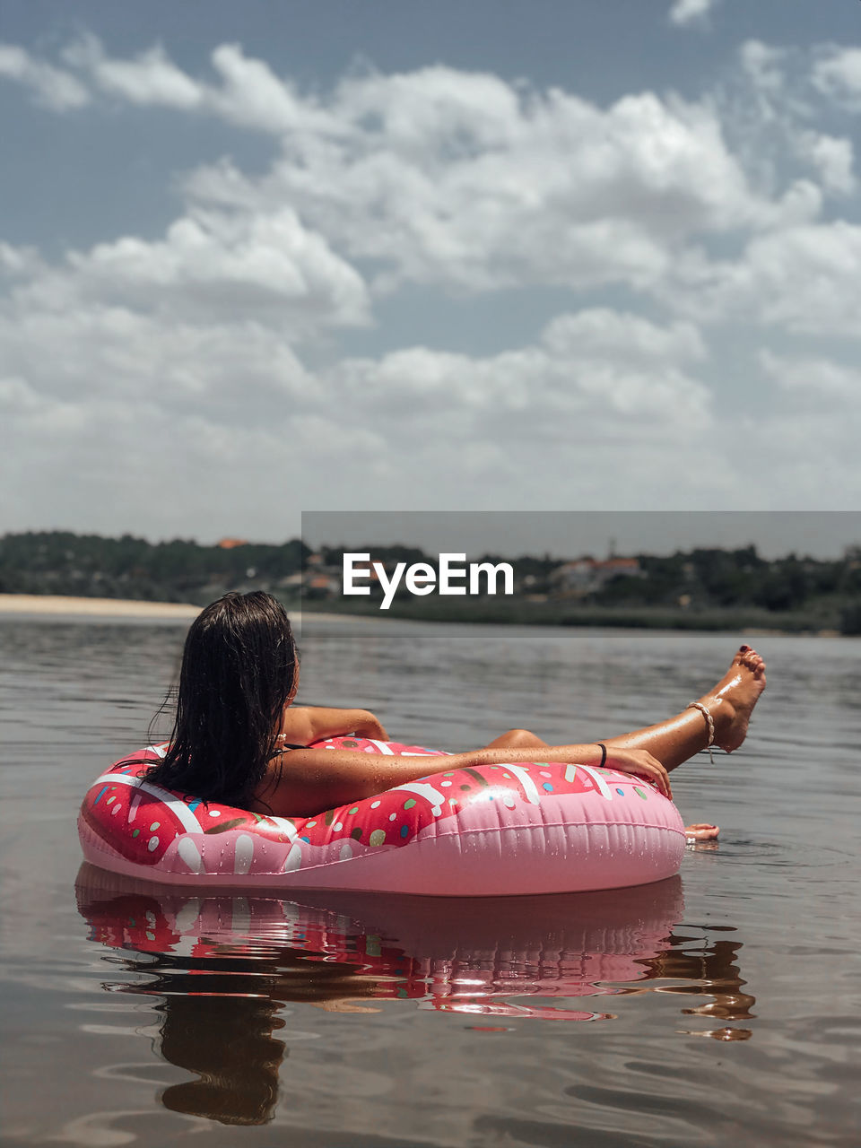 Young woman relaxing on inflatable ring over lake