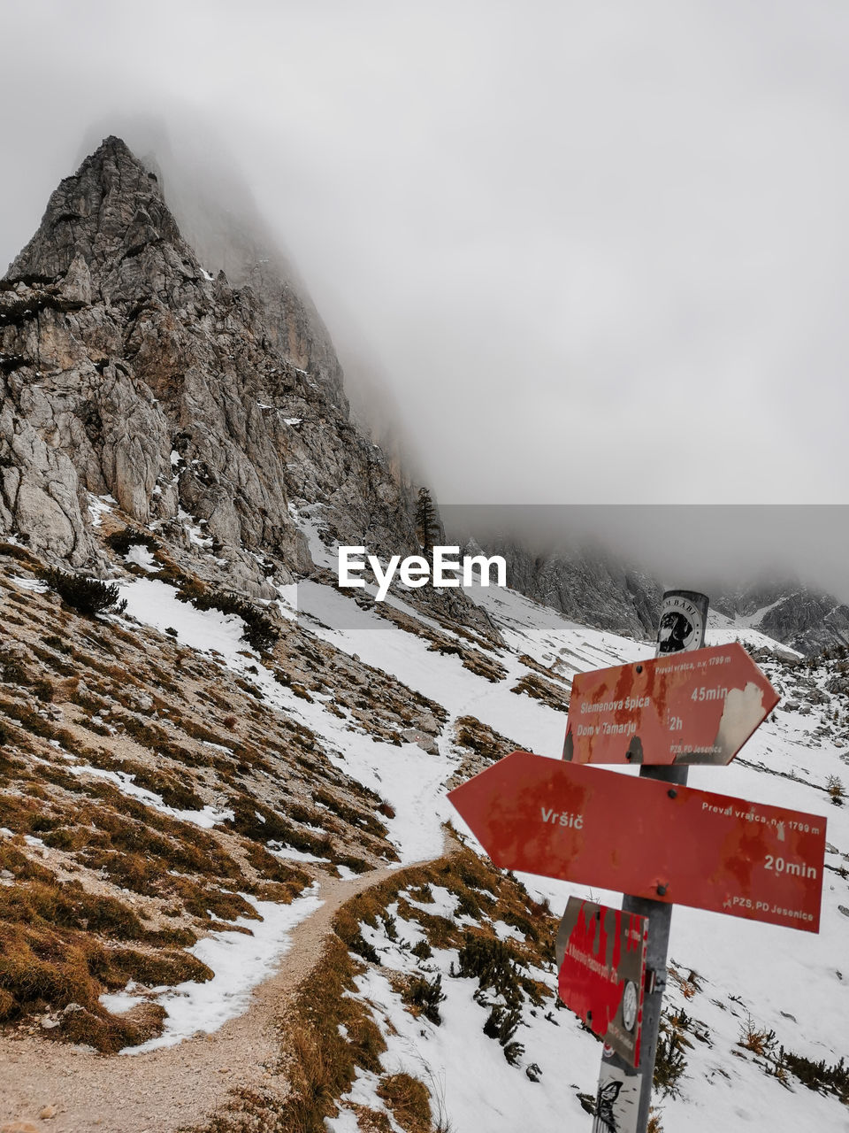 Red hiking trail signs in misty mountains in winter in julian alps in slovenia