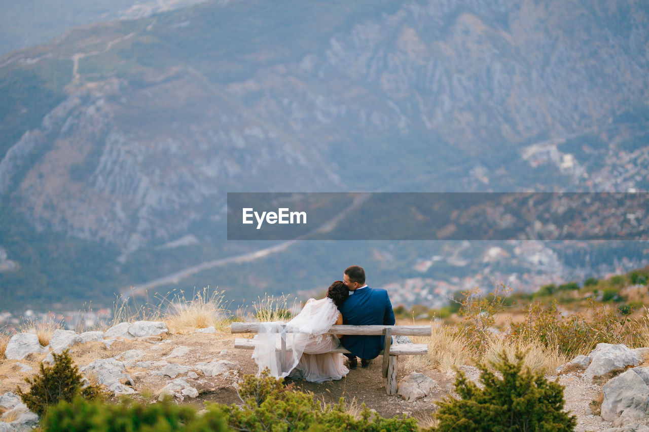 Couple sitting on bench at mountain