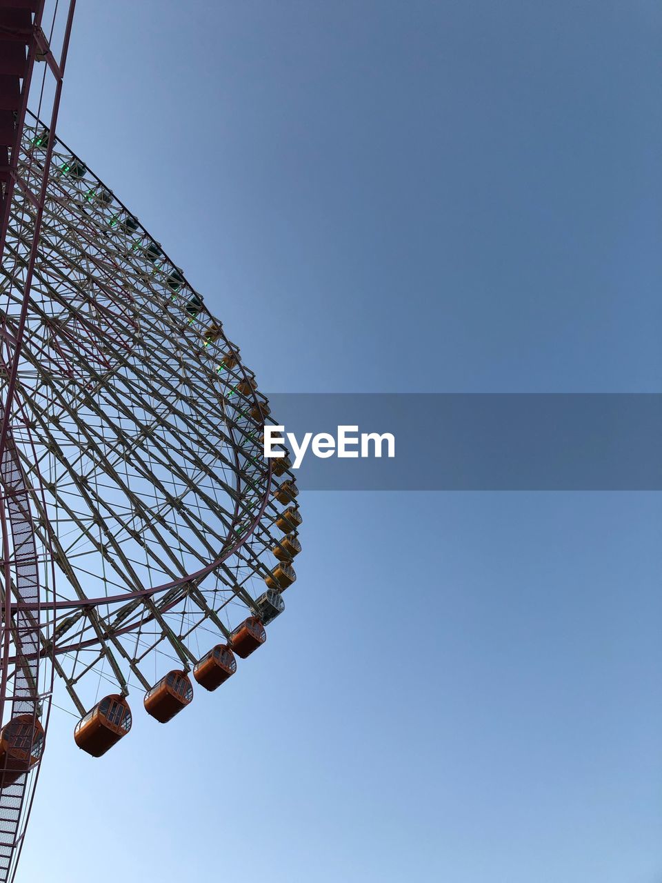 Low angle view of ferris wheel against clear blue sky